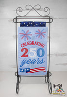 Embroidered mini quilt with 'Celebrating 250 years' text and fireworks design on a stand.