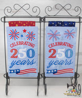 Two decorative mini quilts celebrating 250 years with red, white, and blue designs on a stand.